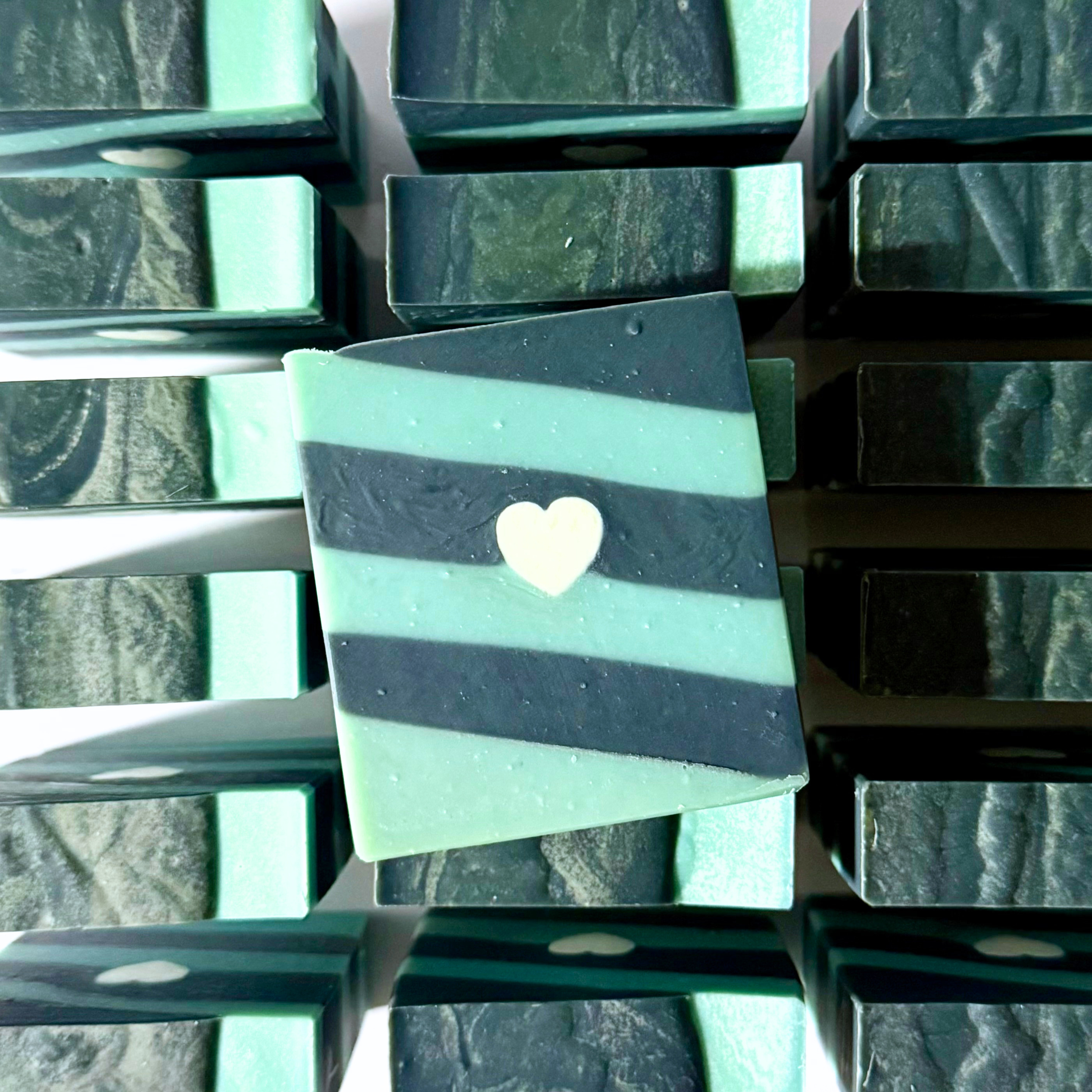 Green and black striped soap with a heart-shaped object on a textured background
