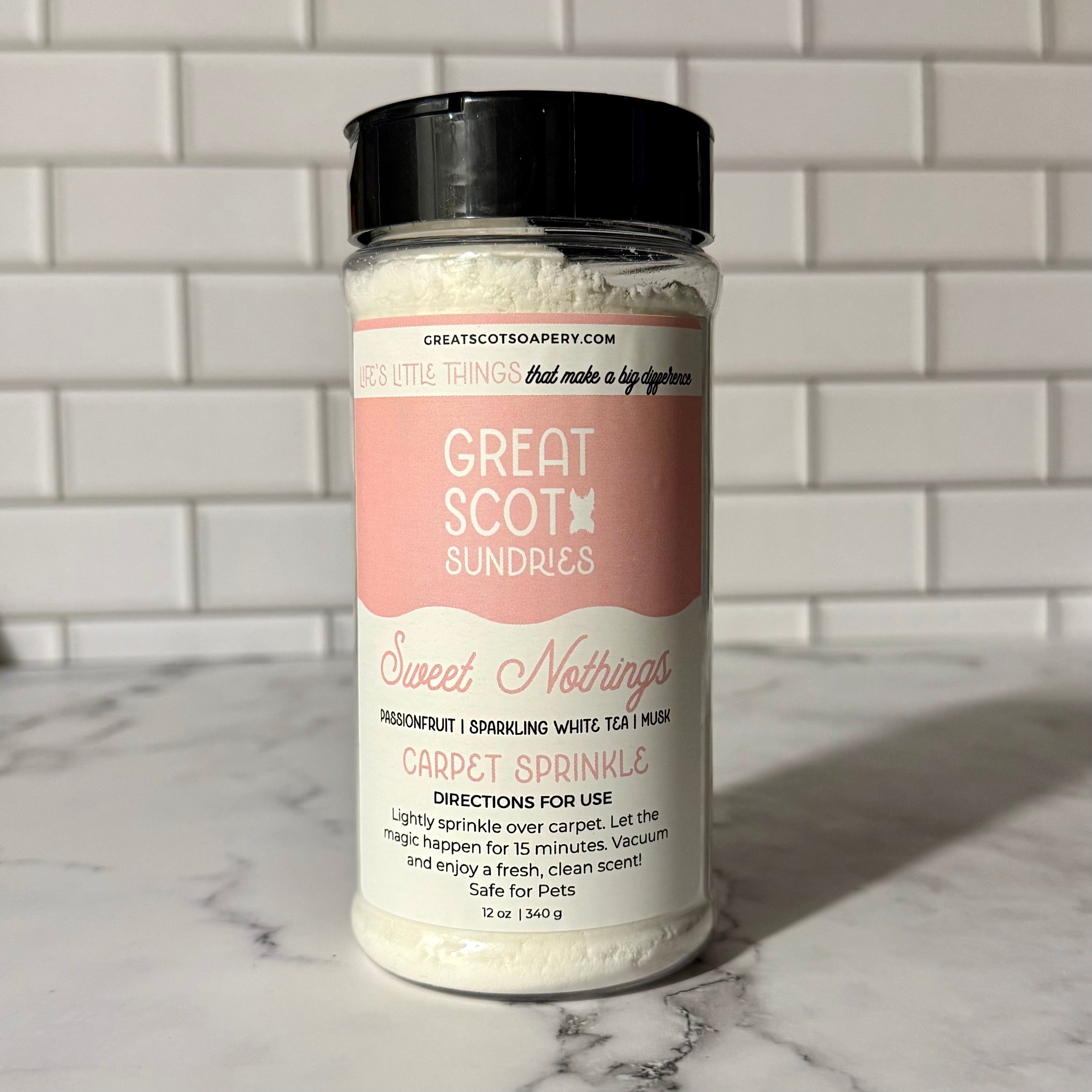 Bottle of 'Sweet Nothings' carpet sprinkle by Great Scot Sundries on a marble surface with a tiled wall background.