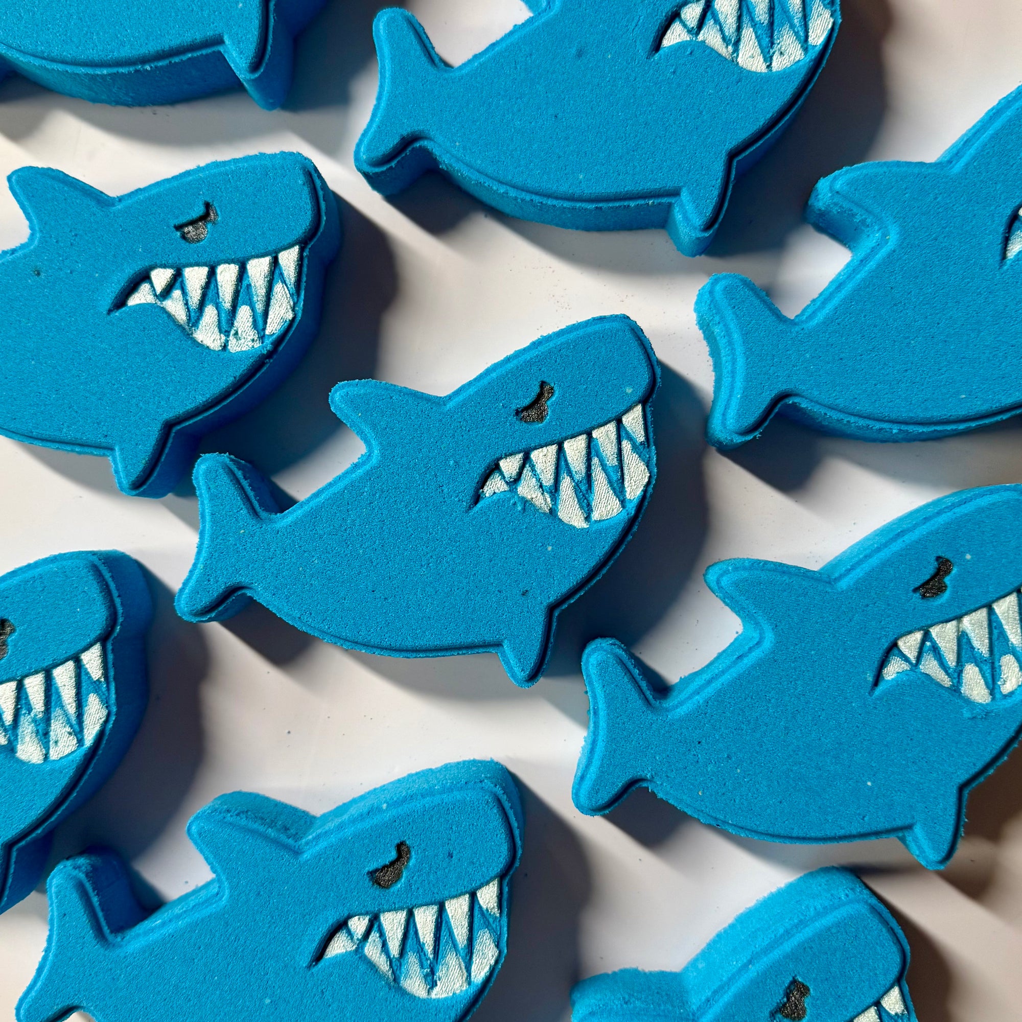 Blue shark-shaped objects with white teeth on a light background