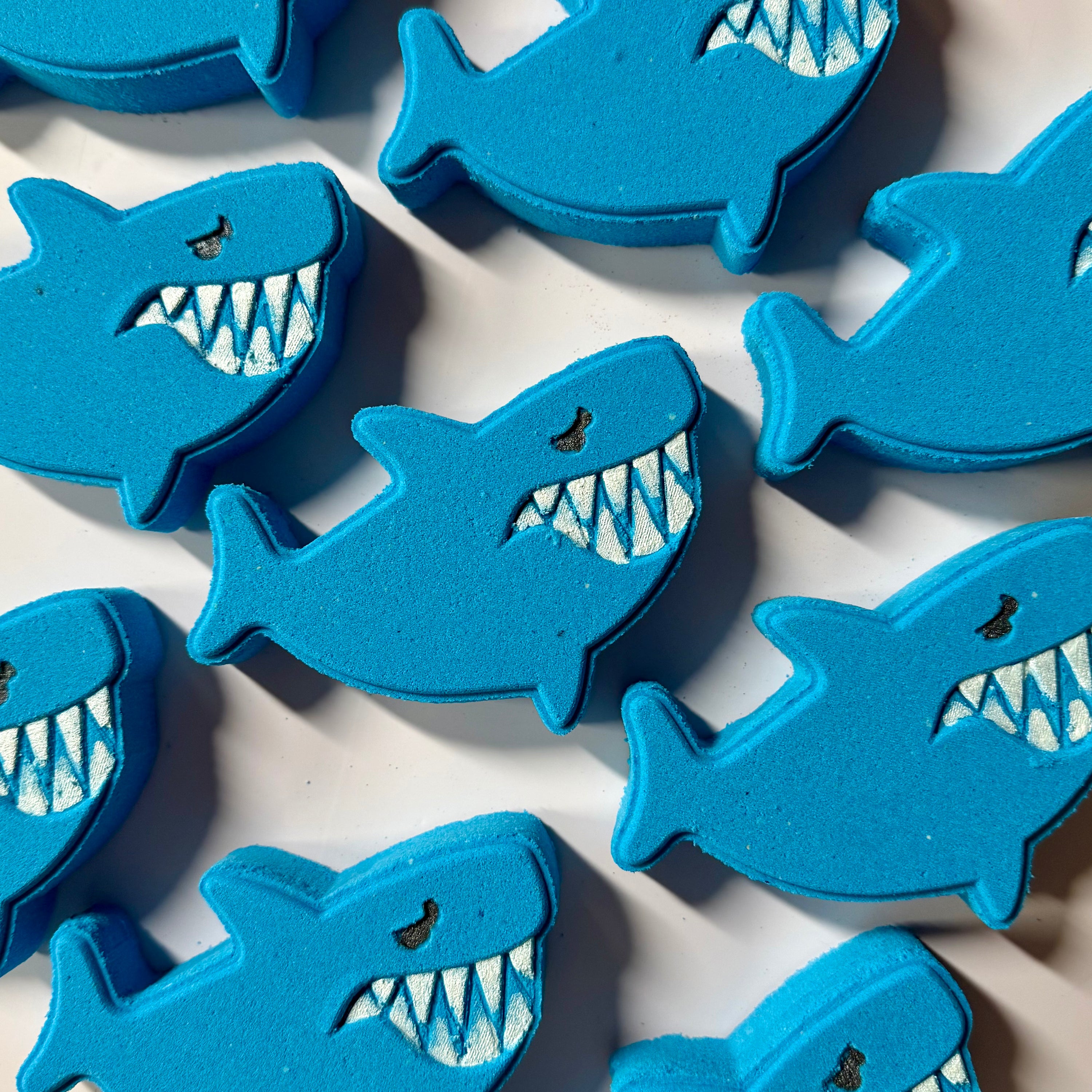 Blue shark-shaped objects with white teeth on a light background