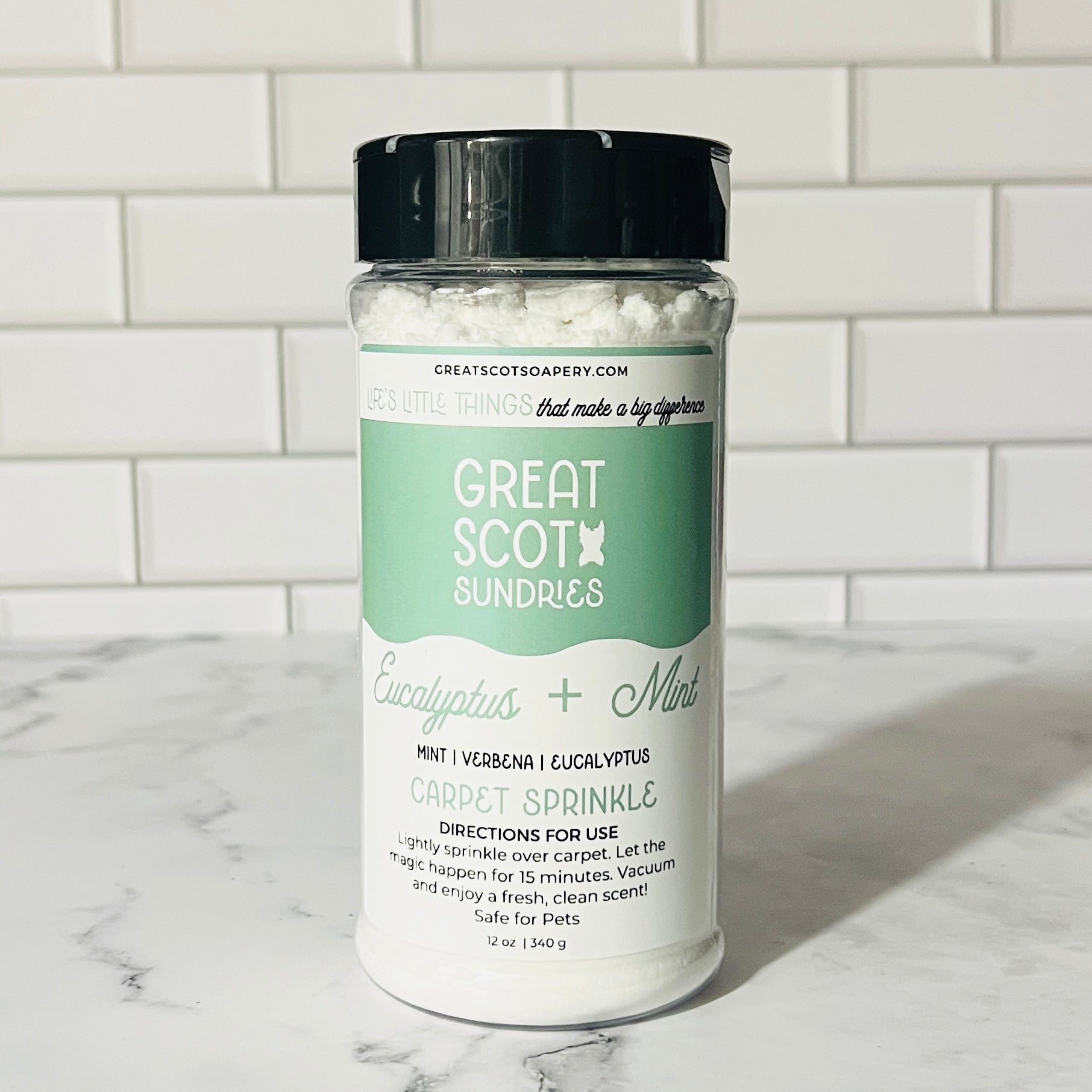Jar of Great Scot Dundries Eucalyptus + Mint carpet sprinkle on a marble surface with a tiled wall background.
