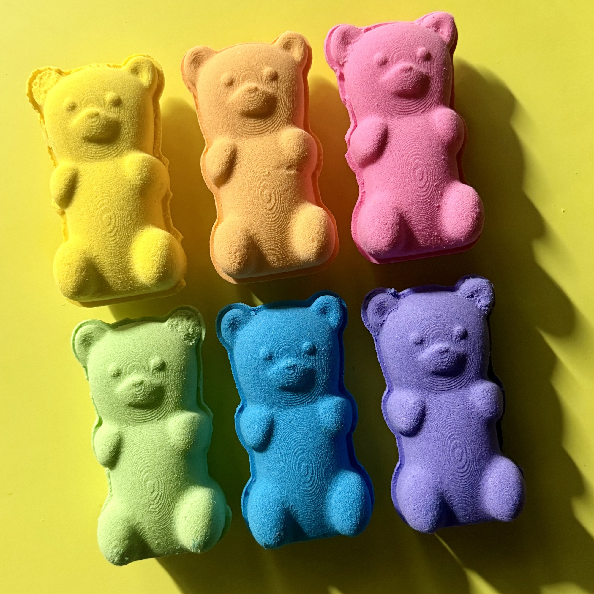 Six colorful bear-shaped objects on a yellow background