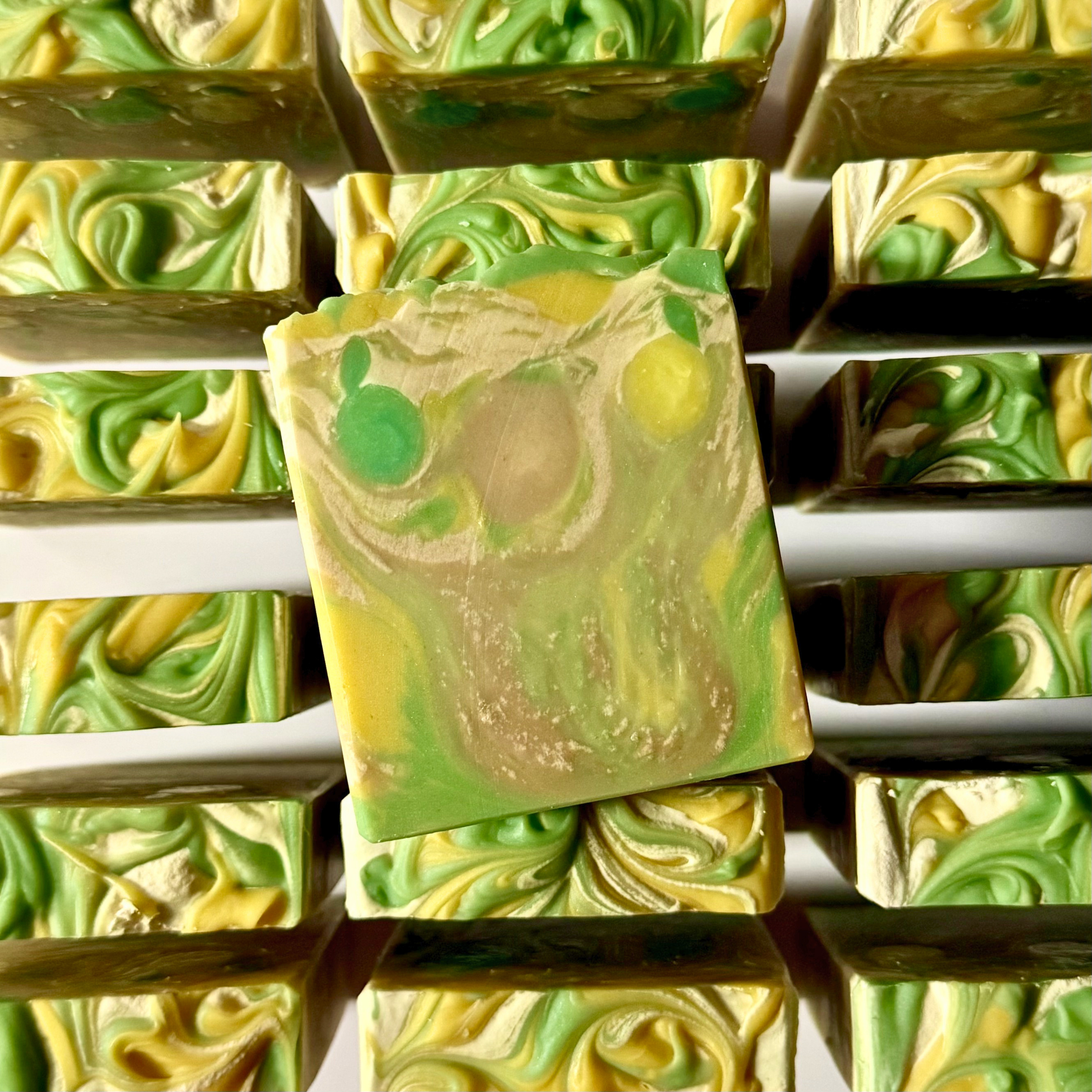 Green and yellow swirled soap bars stacked on a white background