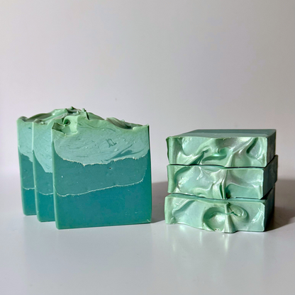 Two bars of green soap with a wavy texture on a white background