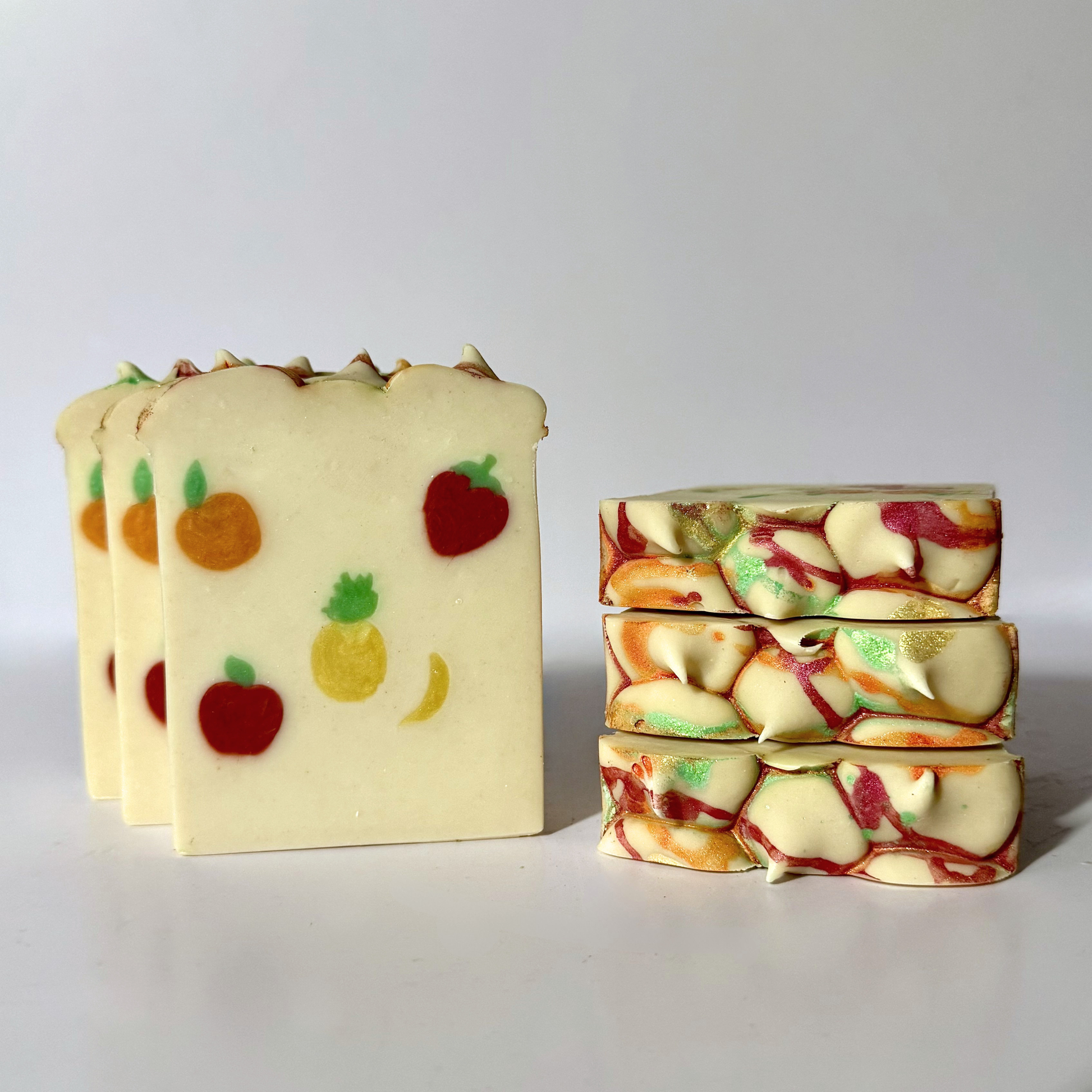 Three bars of soap with fruit designs on a white background