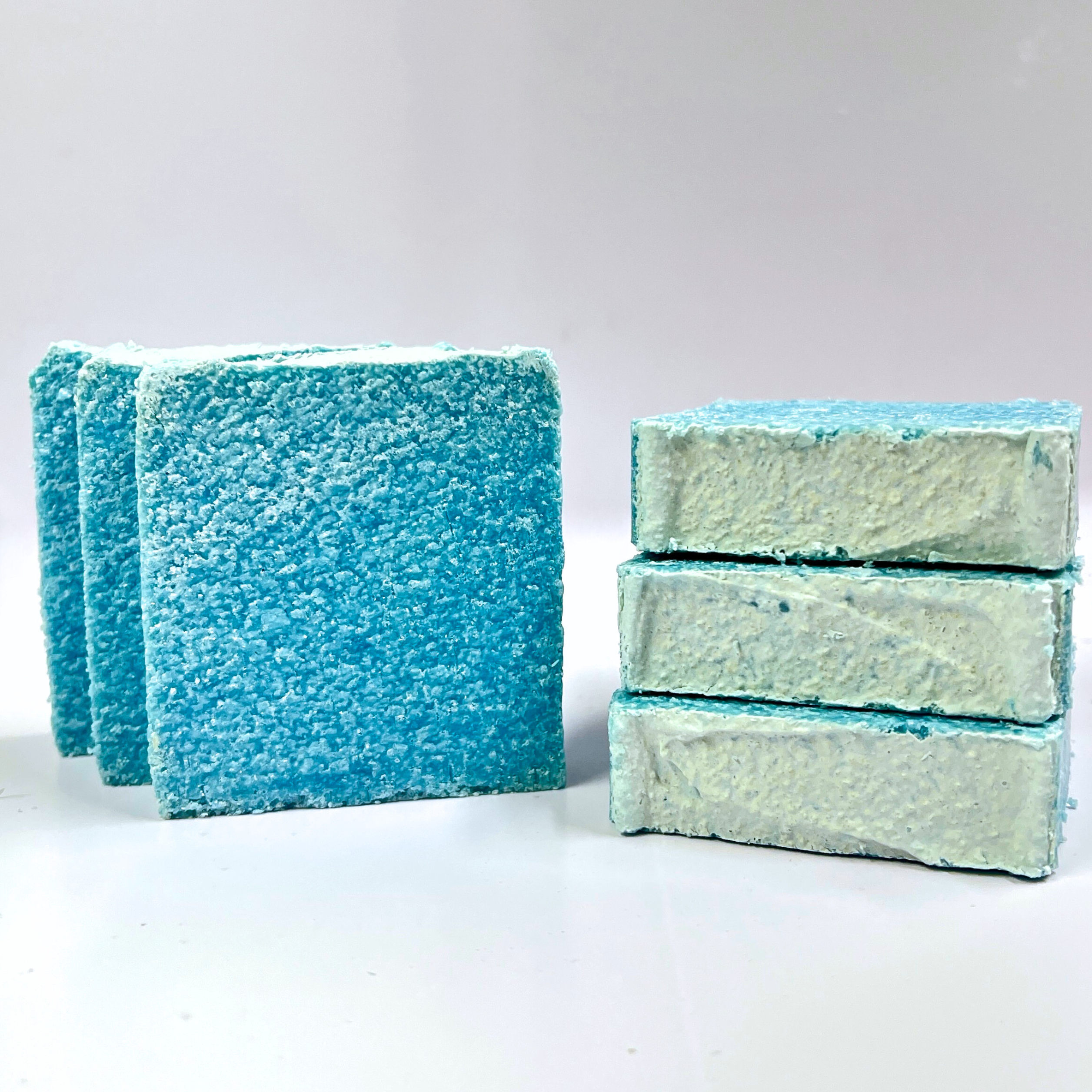Two stacks of blue and green soap bars on a white background