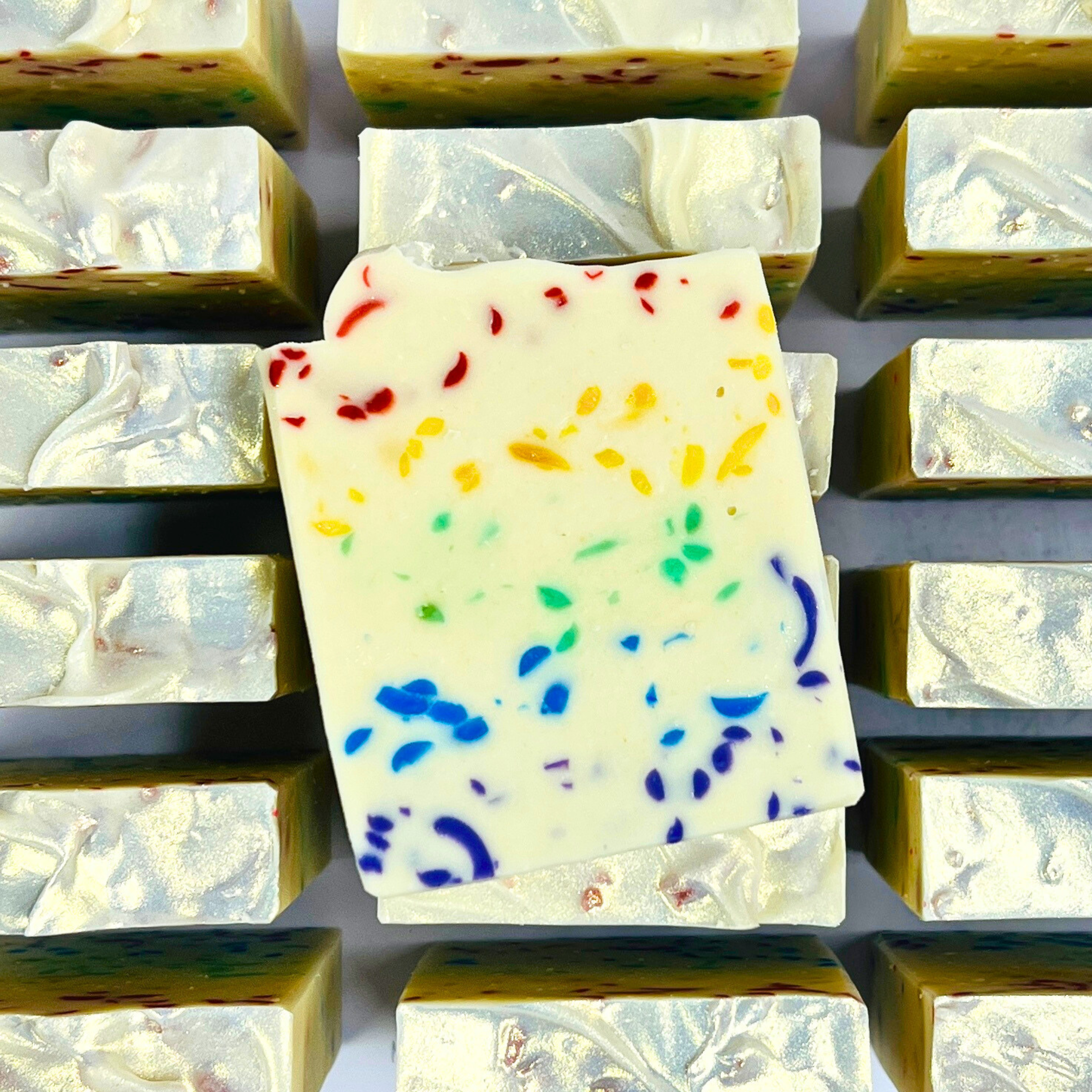 White soap bar with colorful specks on a grid of similar soap bars.