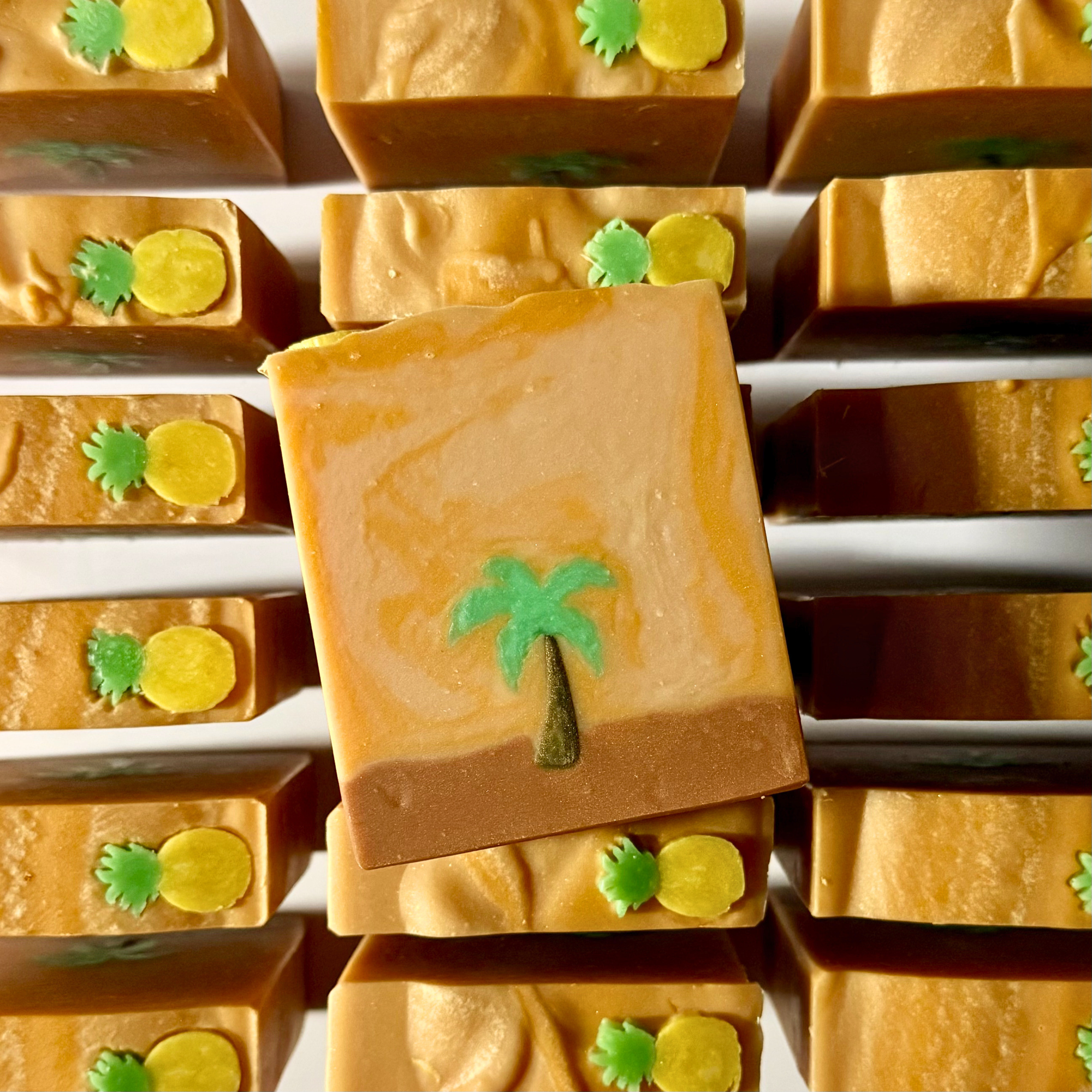 Close-up of pineapple-themed soap bars with decorative elements on a white background