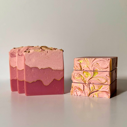 Three pink soap bars with gold accents on a light gray background